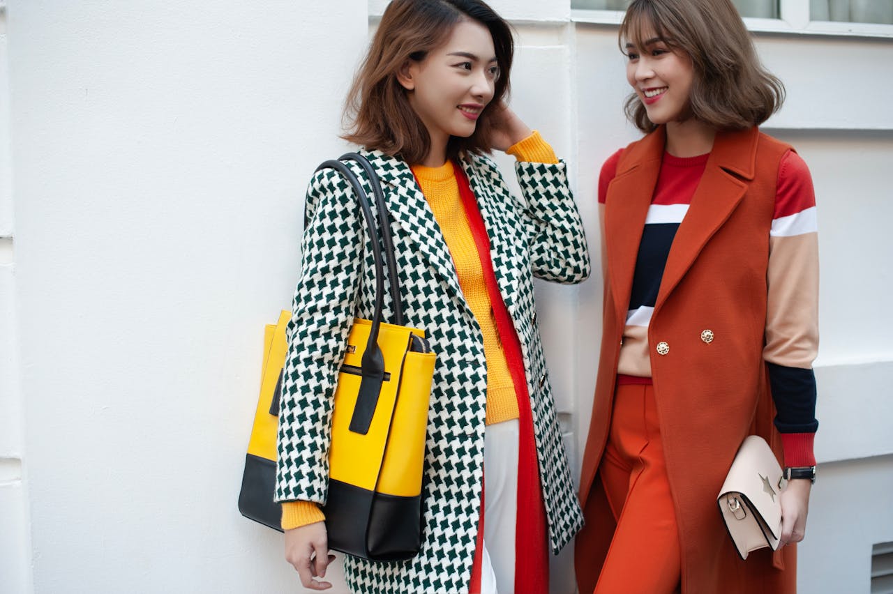 Two women in vibrant winter fashion showcasing trendy coats and accessories.