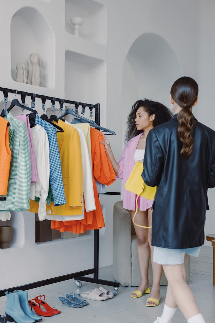 Fashion stylists coordinating outfits in a chic boutique with vibrant apparel selection.