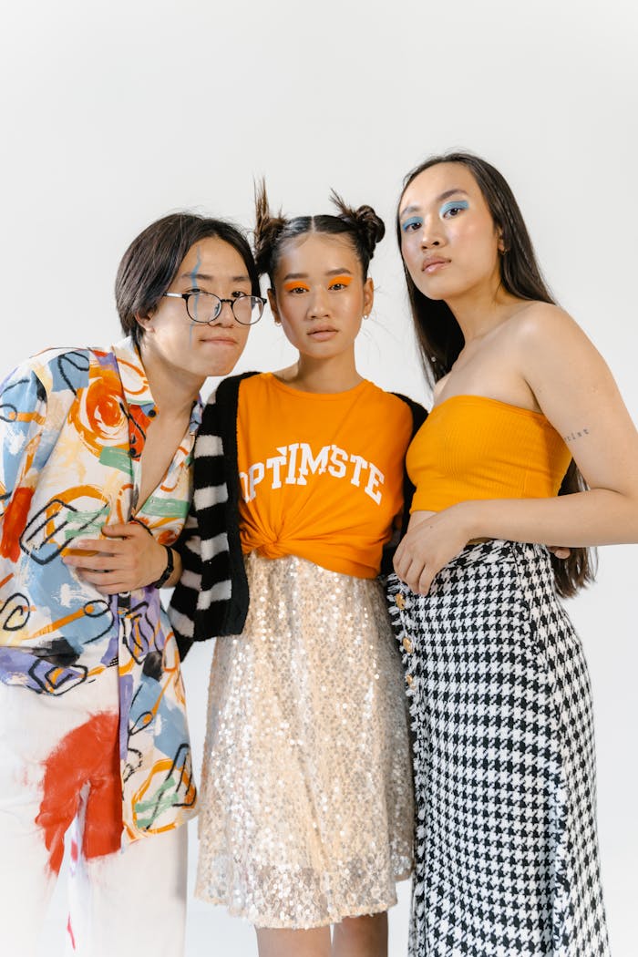 Three stylish teenagers posing confidently in colorful outfits with eye-catching makeup.